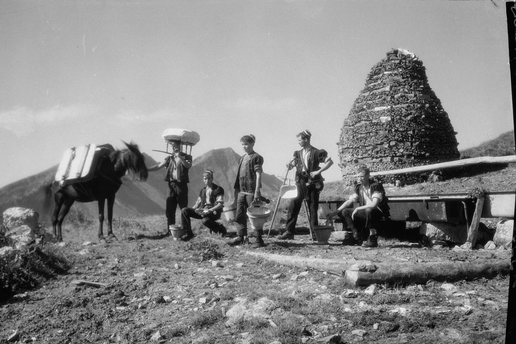 Die Sennen posieren mit ihren Werkzeugen vor der Alphütte und der Holzreserve, um 1930 © Glasson-Musée gruérien