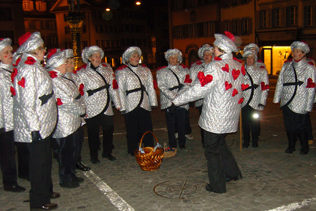 The choir of a folk music group singing and receiving the basket of doughnuts on Kolinplatz square, 2010 © Ernst Moos, Zug