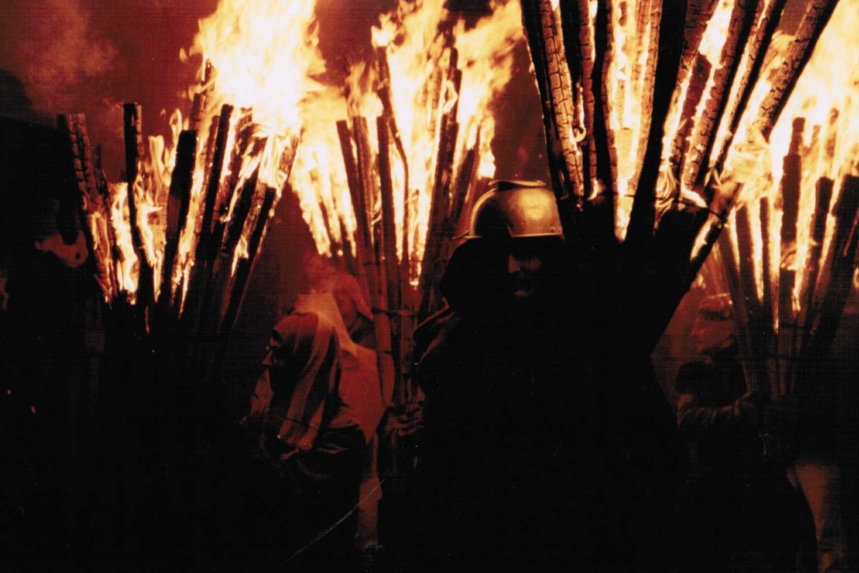 Les participants se protègent des braises avec des casques, ou parfois même avec un égouttoir, 2004 © Hanspeter Meyer