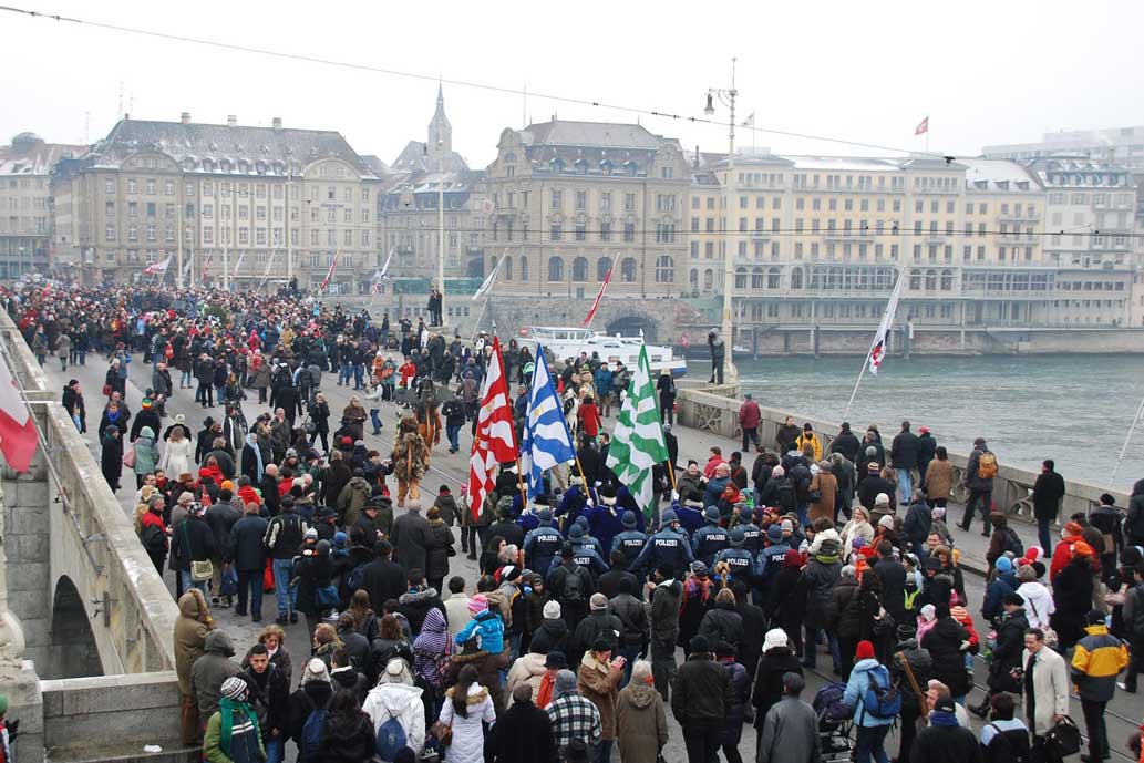 Sur le mittlere Rheinbrücke, les trois personnages dansent pour la population, le dos toujours tourné au Grand-Bâle © Erwin Hensch, 2010