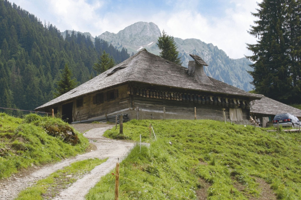 Tegia d'alp en la regiun da la Gruyère cun plumpas che pendan sut in tetg da schlondas © Interprofession du Gruyère AOC